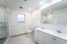 Full bath featuring a baseboard heating unit, a stall shower, a wainscoted wall, and a sink