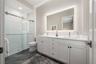 The en-suite bathroom has a double vanity, backlit mirror, porcelain tile flooring and walk-in shower with glass door.