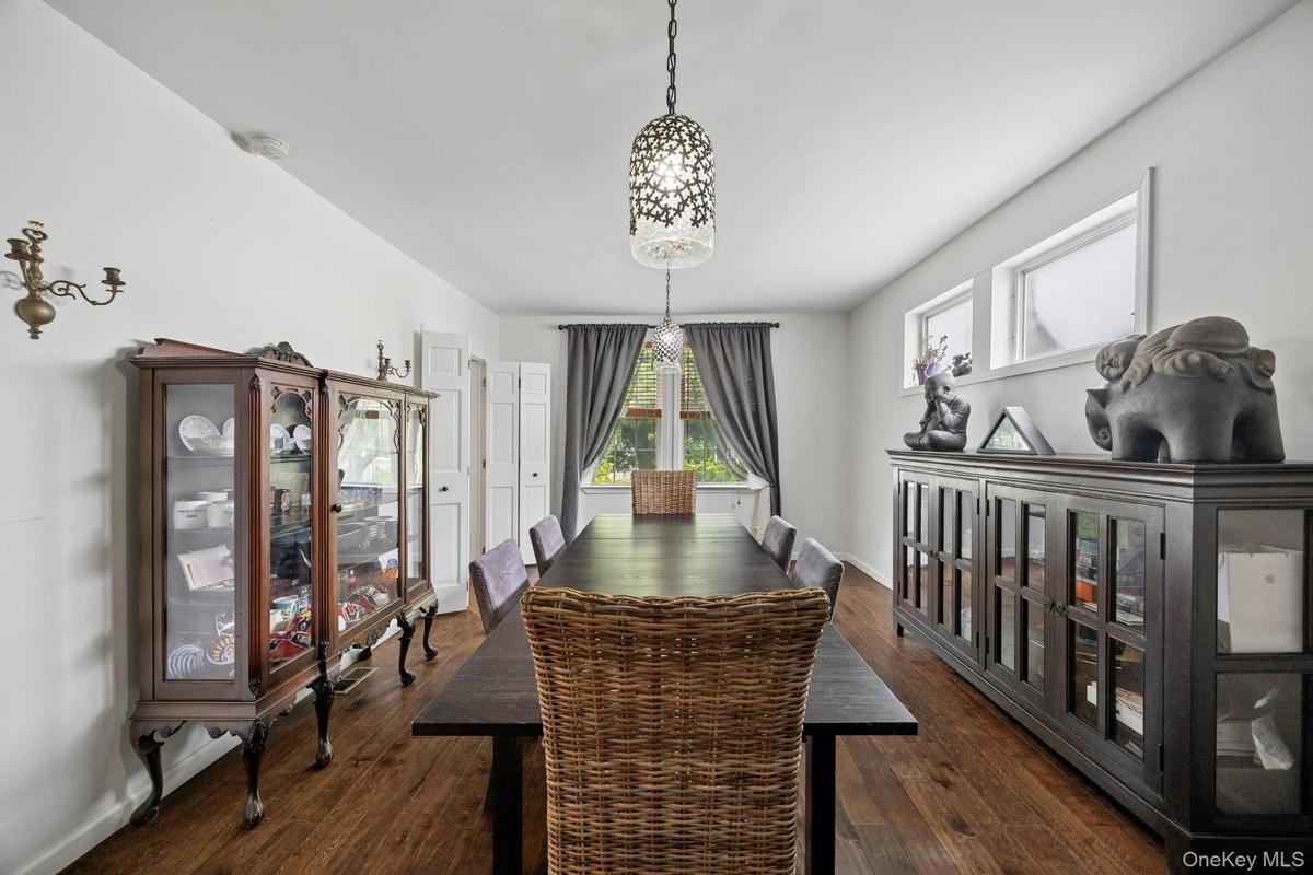 Spacious formal dining room featuring rich hardwood flooring, oversized windows that provide abundant natural light, and elegant lighting fixtures. Th