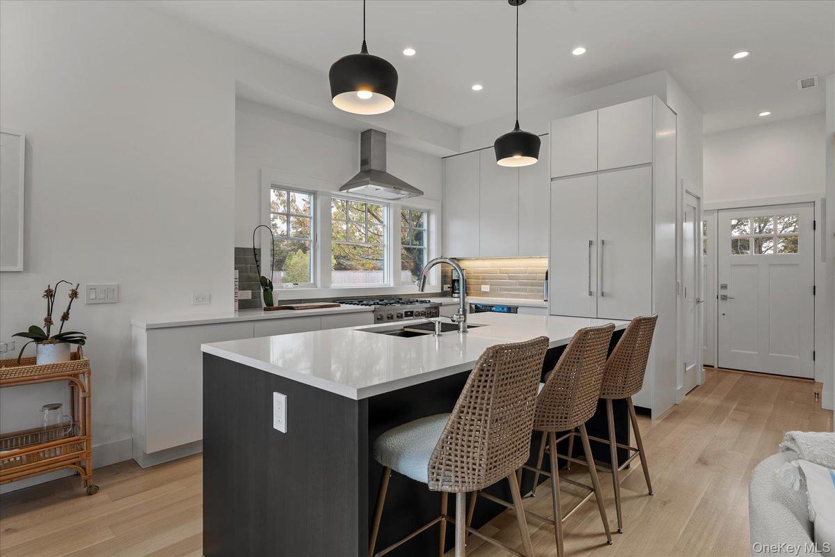 Kitchen with a kitchen bar, a kitchen island with sink, pendant lighting, modern cabinets, and light wood-type flooring