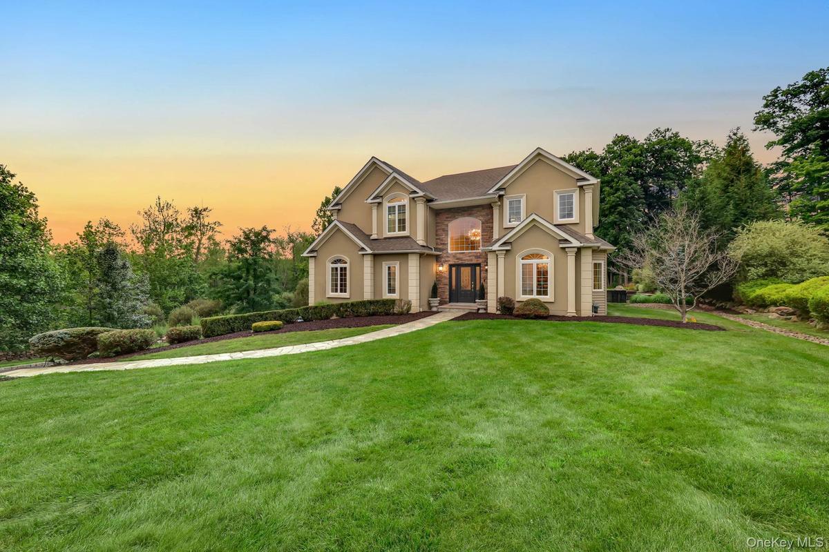 Stucco exterior with stone accents, arched entryway, bay windows, and a paved walkway