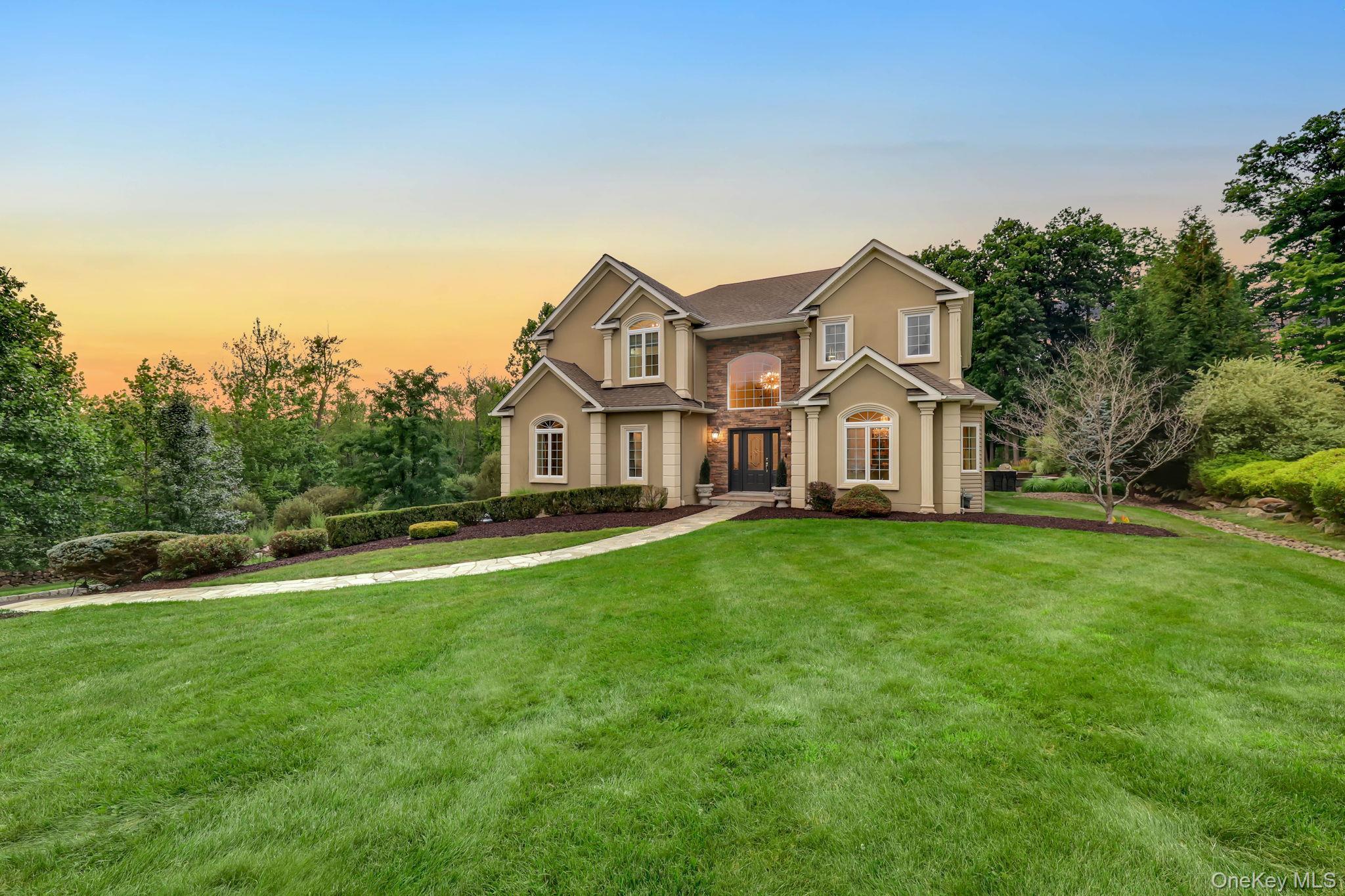 Stucco exterior with stone accents, arched entryway, bay windows, and a paved walkway