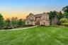 Stucco exterior with stone accents, arched entryway, bay windows, and a paved walkway