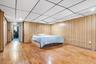 Bedroom featuring a paneled ceiling, hardwood / wood-style flooring, and wooden walls