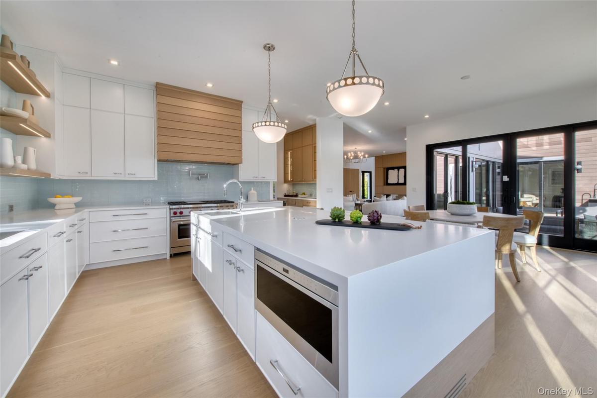 Kitchen featuring open shelves, appliances with stainless steel finishes, a large island, light wood-style floors, and white cabinets