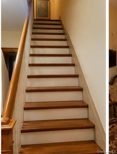 Staircase featuring wood-finish treads and risers, a wood handrail, and white balusters