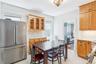 Kitchen featuring high quality fridge, tasteful backsplash, radiator, and glass insert cabinets