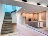 (as of April 8, 2026) a gorgeous floating concrete staircase anchors the living area under a double-height ceiling, glass railings are in the process 