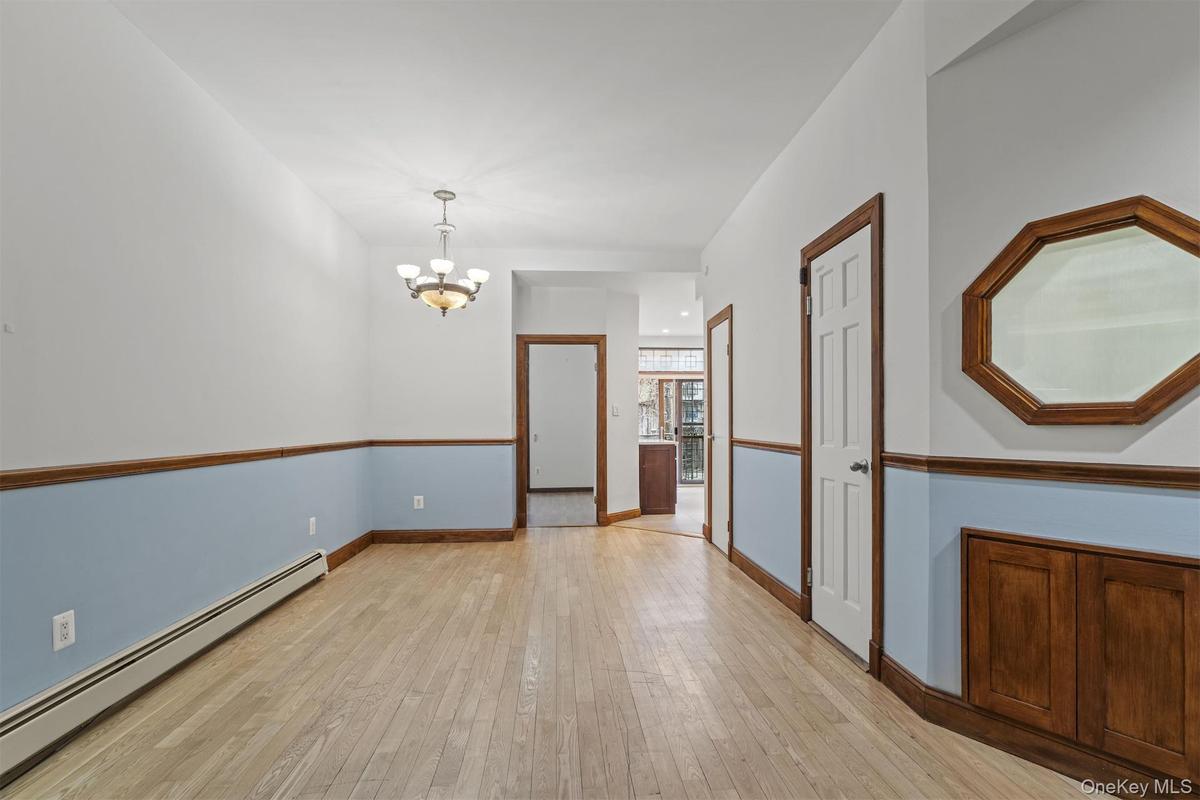 Spare room featuring a baseboard heating unit, a chandelier, and light wood-style floors