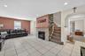 Living room featuring light tile patterned floors, a stone fireplace, recessed lighting, and stairway
