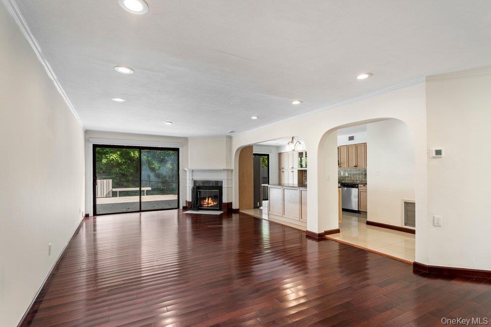Spacious living area featuring rich wood-finish flooring, recessed lighting, and a stone-surround fireplace