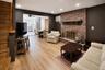 Brick fireplace with a stone hearth, wood-finish flooring, and recessed lighting