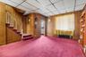 Carpeted living room featuring wood walls, stairway, baseboards, and a paneled ceiling