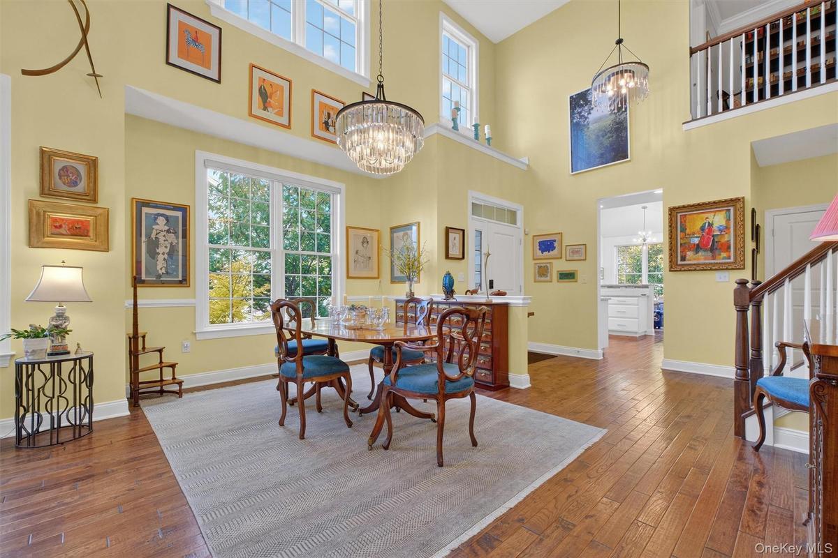 Dining space with dark wood finished floors, stairway, a towering ceiling, and a chandelier