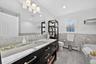 Bathroom featuring a bath, wainscoting, tile walls, vanity, and a baseboard radiator