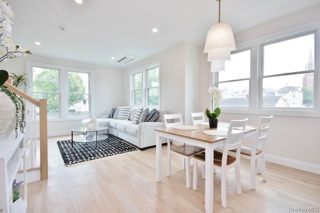 Dining space featuring light wood-type flooring, stairs, healthy amount of natural light, and recessed lighting