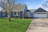 View of front of property featuring concrete driveway, a front lawn, and an attached garage