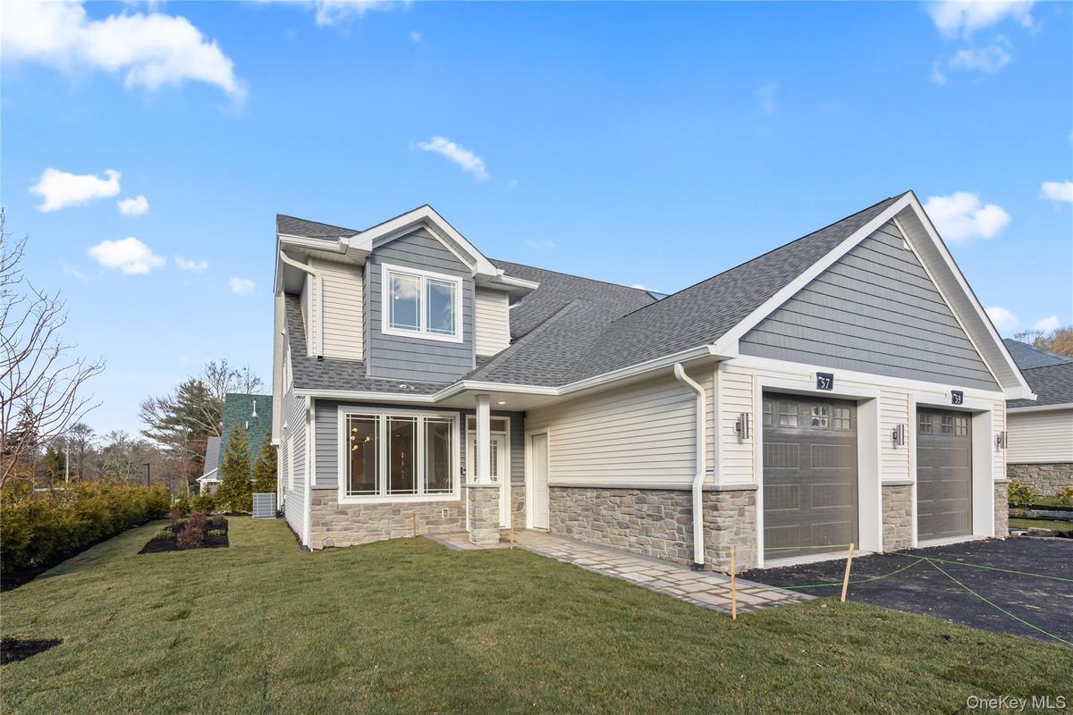 View of front facade with roof with shingles, stone siding, an attached garage, asphalt driveway, and a front lawn