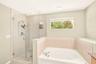 Primary en-suite bathroom featuring a large glass enclosed shower, large garden tub