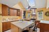Kitchen with tasteful backsplash, brown cabinets, light tile patterned floors, stainless steel appliances, and wall chimney range hood