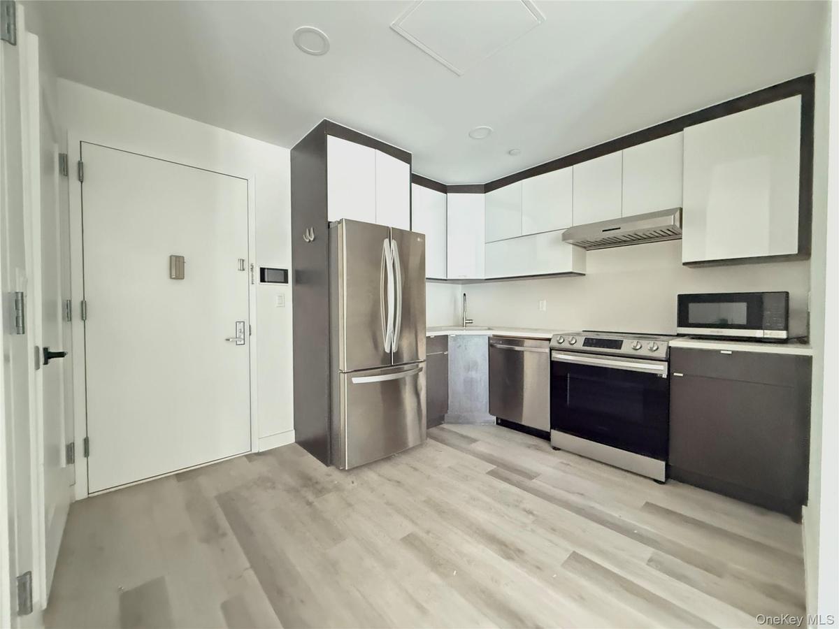 Kitchen with white cabinetry, stainless steel appliances, light countertops, modern cabinets, and light wood-type flooring