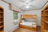 Bedroom with ornamental molding, baseboard heating, light wood finished floors, a ceiling fan, and cooling unit