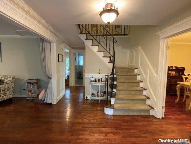 Stairs with crown molding and wood finished floors