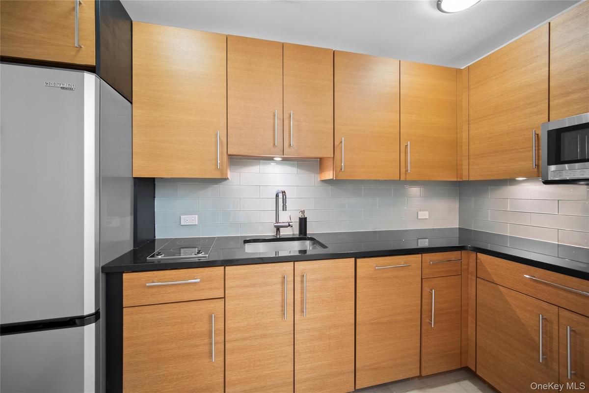 Kitchen featuring appliances with stainless steel finishes, a sink, tasteful backsplash, and dark stone counters