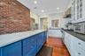 Kitchen with dark hardwood / wood-style flooring, backsplash, brick wall, blue cabinets, and built in appliances