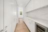 Galley-style kitchen featuring abundant white cabinetry, light wood-finish flooring, and integrated appliances