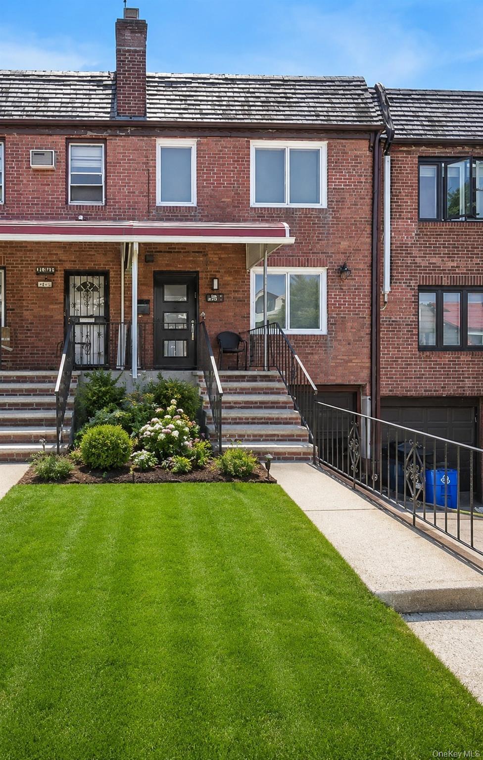 Brick facade home featuring a covered front porch, concrete front steps with metal railings, and a concrete driveway