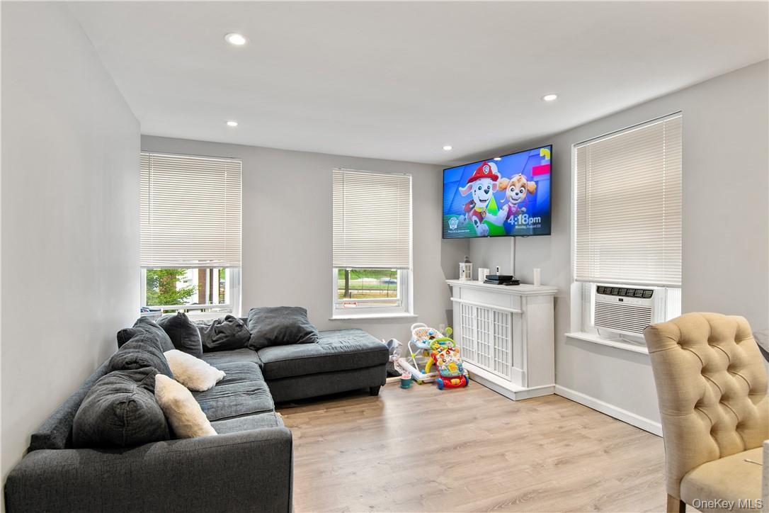 Living area featuring recessed lighting, wood-finish flooring, and multiple windows with blinds