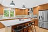 Kitchen featuring stainless steel fridge, a kitchen breakfast bar, light wood finished floors, hanging light fixtures, and recessed lighting