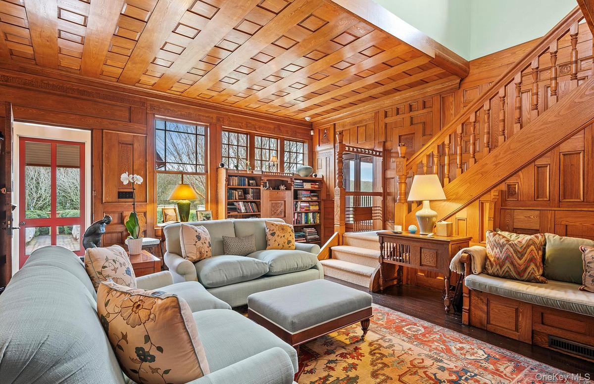 Living area featuring crown molding, wood walls, wood finished floors, and stairs