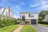 Contemporary residence featuring a brick walkway, manicured lawn, and an attached garage