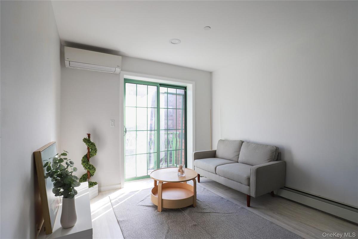 Living room with a baseboard heating unit, wood finished floors, and a wall mounted air conditioner