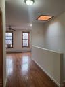 Empty room with a baseboard radiator, wood-type flooring, cooling unit, and a healthy amount of sunlight