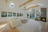 Living room with beamed ceiling, light hardwood / wood-style flooring, high vaulted ceiling, and a tiled fireplace