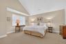Bedroom with high vaulted ceiling and light colored carpet