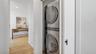 Washroom with stacked washer / drying machine, wood finished floors, and laundry area