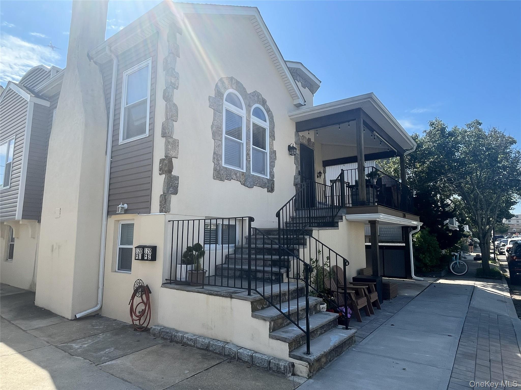 View of front facade featuring stairway and stucco siding