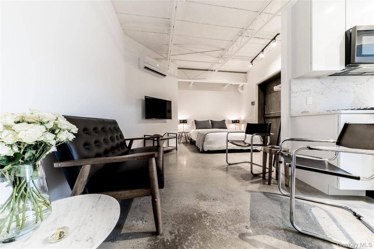 Living room featuring finished concrete flooring and a wall unit AC