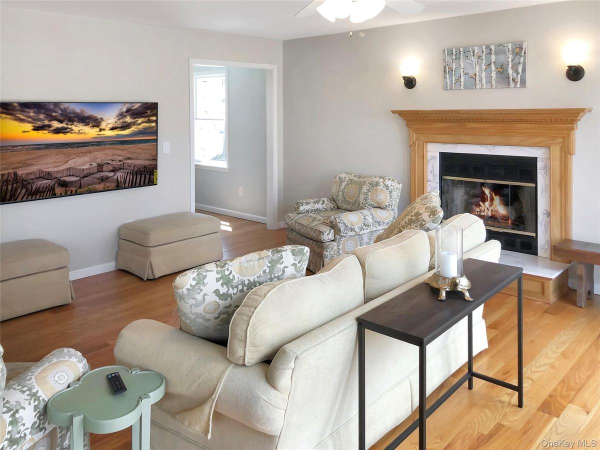 Living room with wood finished floors, a high end fireplace, and a ceiling fan