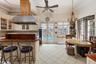 Kitchen with french doors, light tile patterned floors, glass insert cabinets, extractor fan, and a kitchen breakfast bar