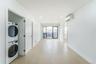 Laundry area featuring light wood finished floors, stacked washer / drying machine, a wall mounted air conditioner, and recessed lighting