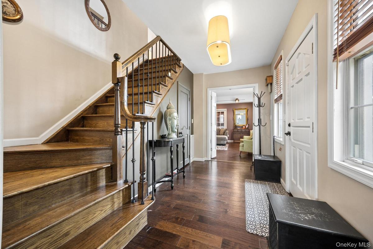 Inviting entrance foyer featuring rich hardwood flooring, a beautifully crafted staircase with classic wood balusters, and an open layout that creates