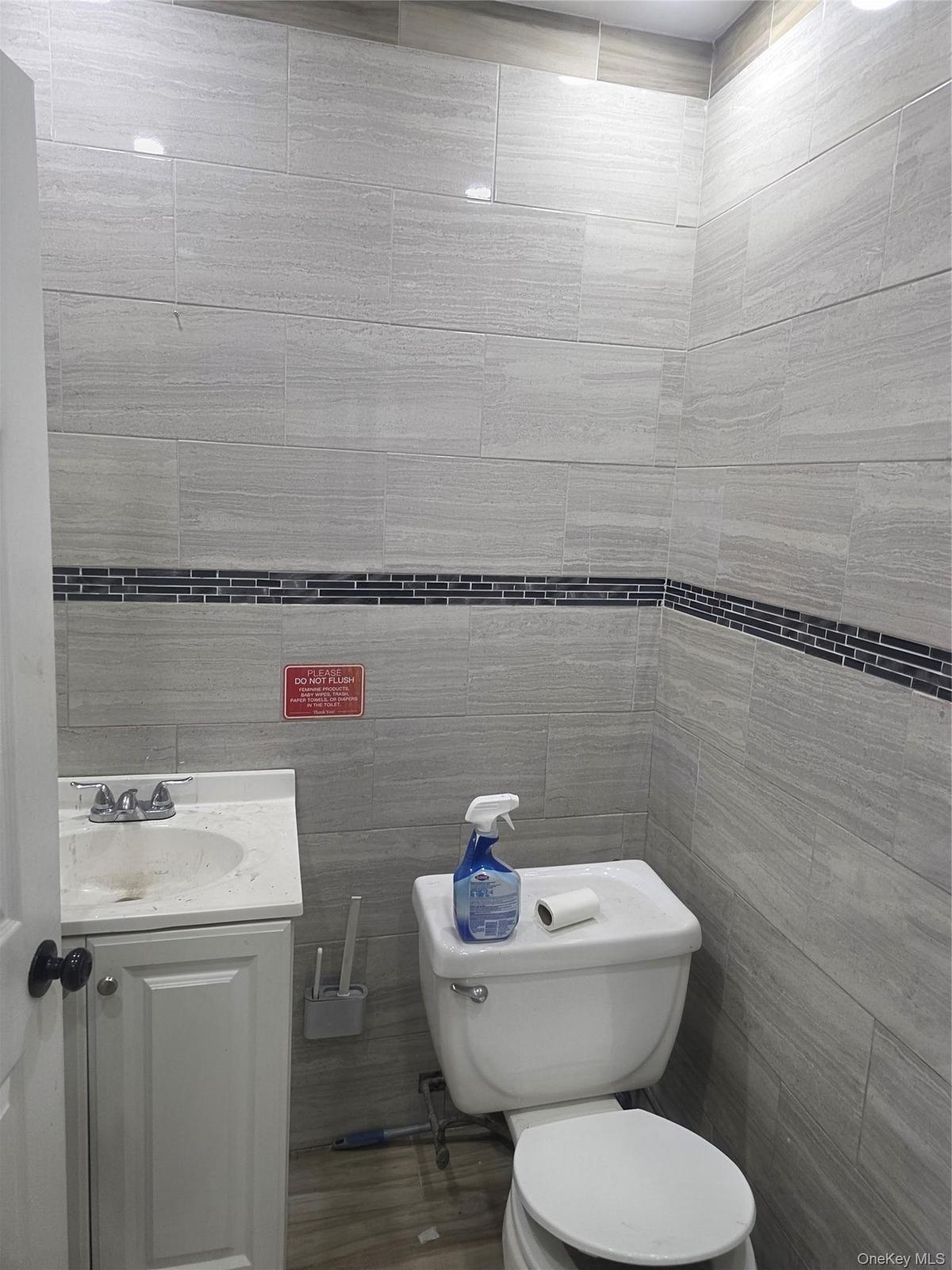 Bathroom featuring light gray horizontal tile walls with a dark mosaic accent band