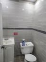 Bathroom featuring light gray horizontal tile walls with a dark mosaic accent band