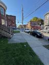View of asphalt street featuring sidewalks, curbs, and street lighting