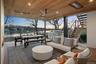 Patio terrace at dusk with outdoor lounge area, ceiling fan, exterior kitchen, grilling area, and a water view